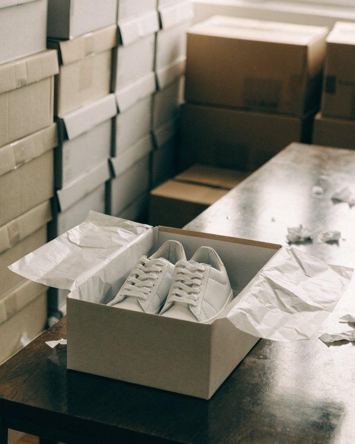 Caja abierta con un par de zapatillas blancas en la mesa de preparación