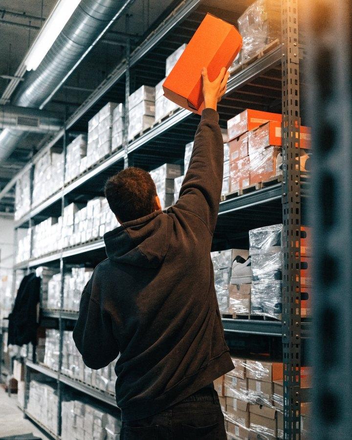 Operario sacando una caja de zapatillas de la estantería
